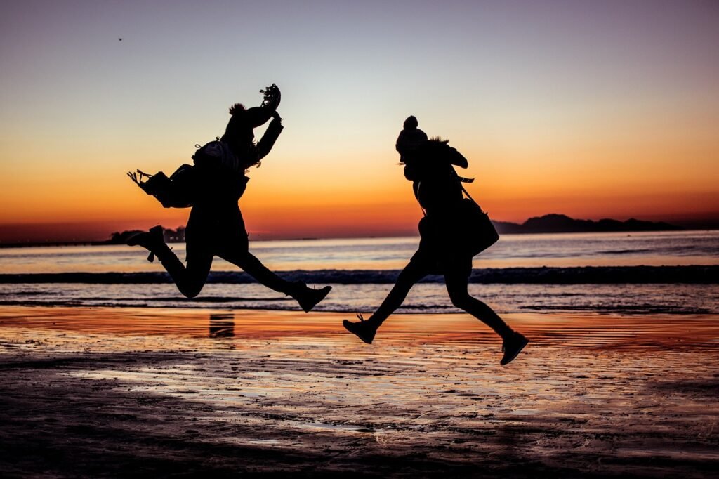 Two people playing in the ocean at sunset